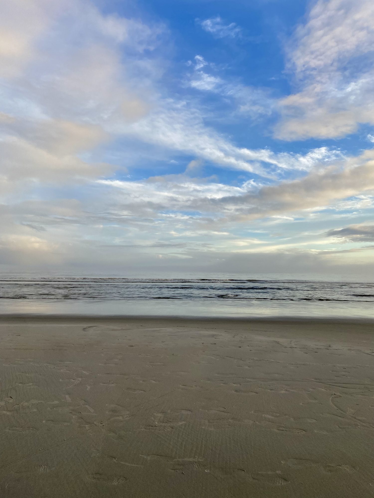 Beach at sunrise, low cloud over breaking waves.