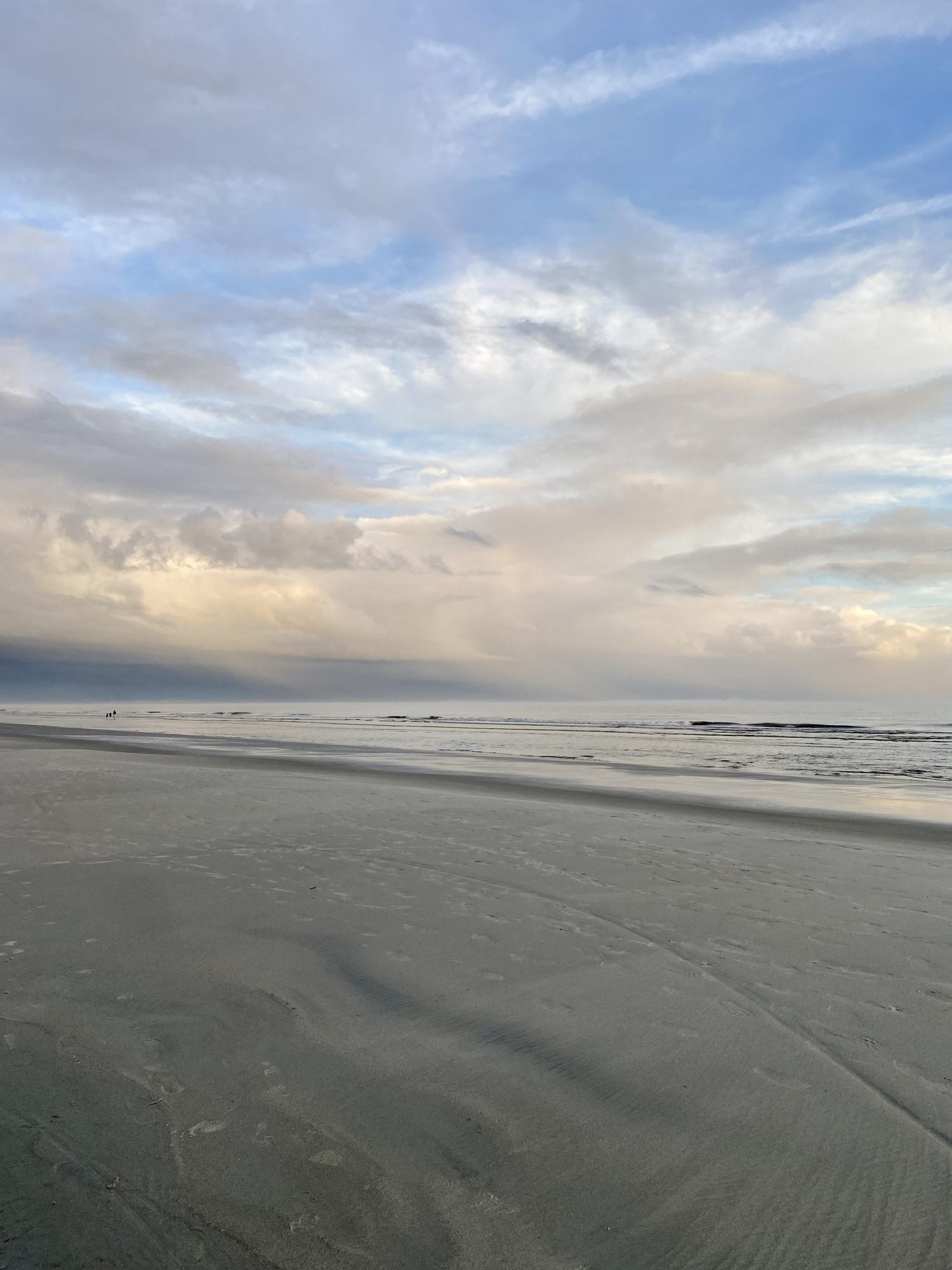 Beach at dusk, cloud and sand meeting a flat sea.